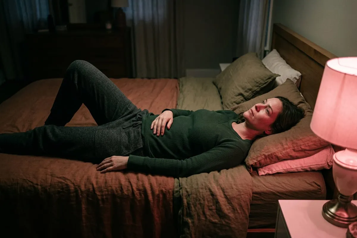 女人躺在床上望著天花板，燈光昏黃，靜靜承受