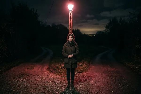 女人站在夜晚的路口，玫瑰燈光下面對人生的抉擇